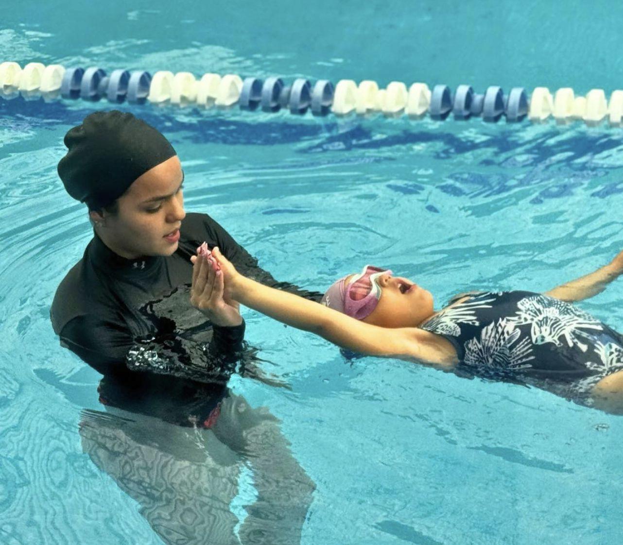 Niños aprendiendo a nadar en grupo con instructor